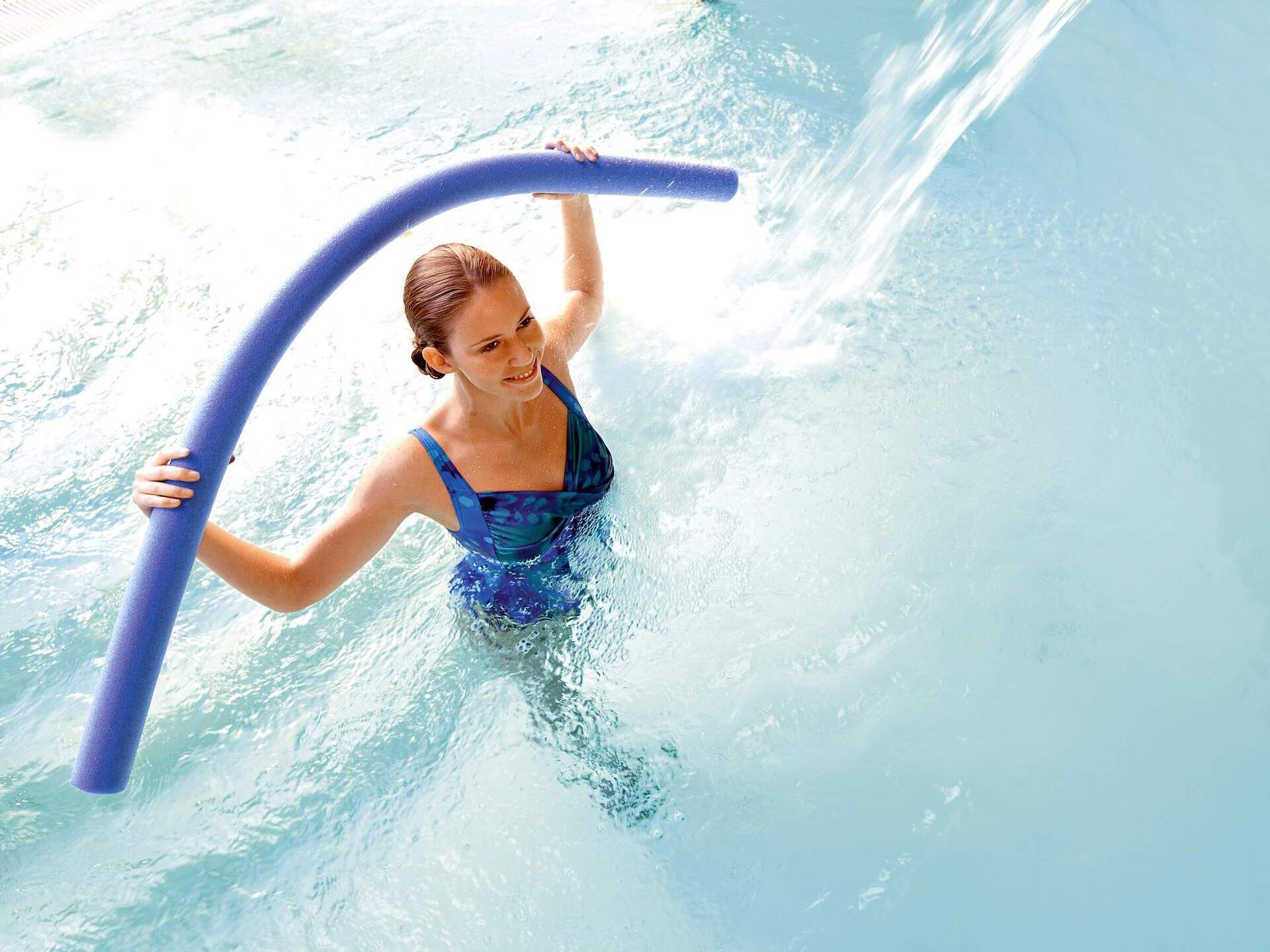 Eine junge Frau macht Wassergymnastik im Pool einer Therme von Bad Füssing.