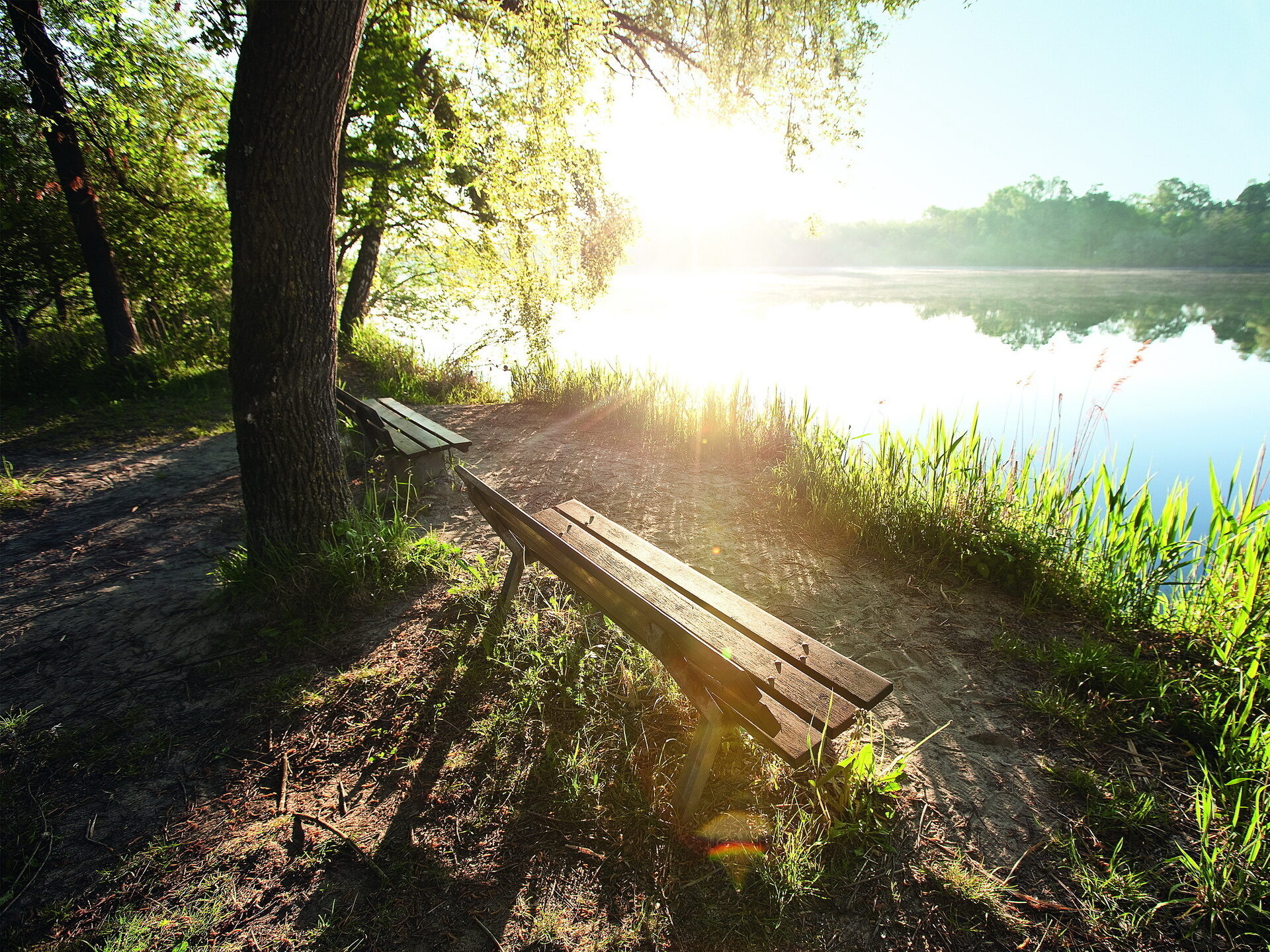 Eine gem&uuml;tliche Bank zum sitzen mit Blick auf den blau schimmernden sonnenbeleuchteten Inn von Bad F&uuml;ssing.