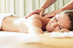 Eine glückliche Frau entspannt bei einer Massage in einem Wellnessbereich von einem Hotel in Bad Füssing.