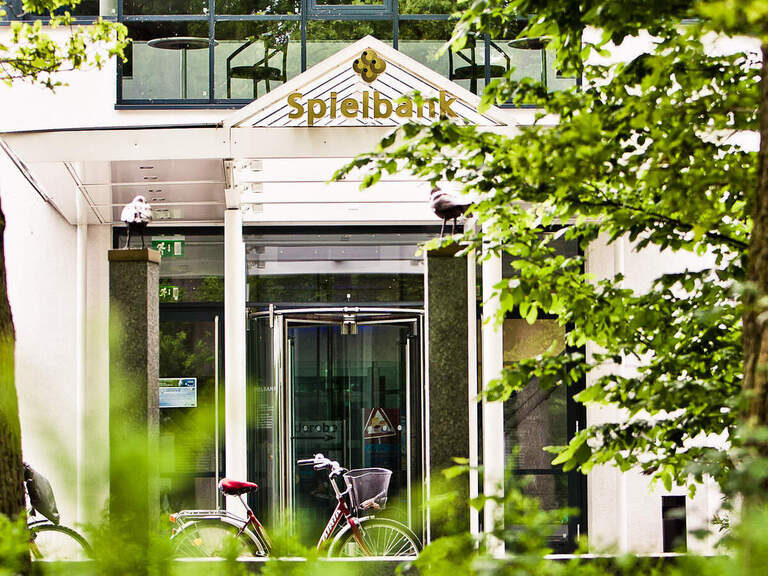 Ein imposantes Spielbankgebäude umgeben von grünen Bäumen inmitten vom Zentrum von Bad Füssing.